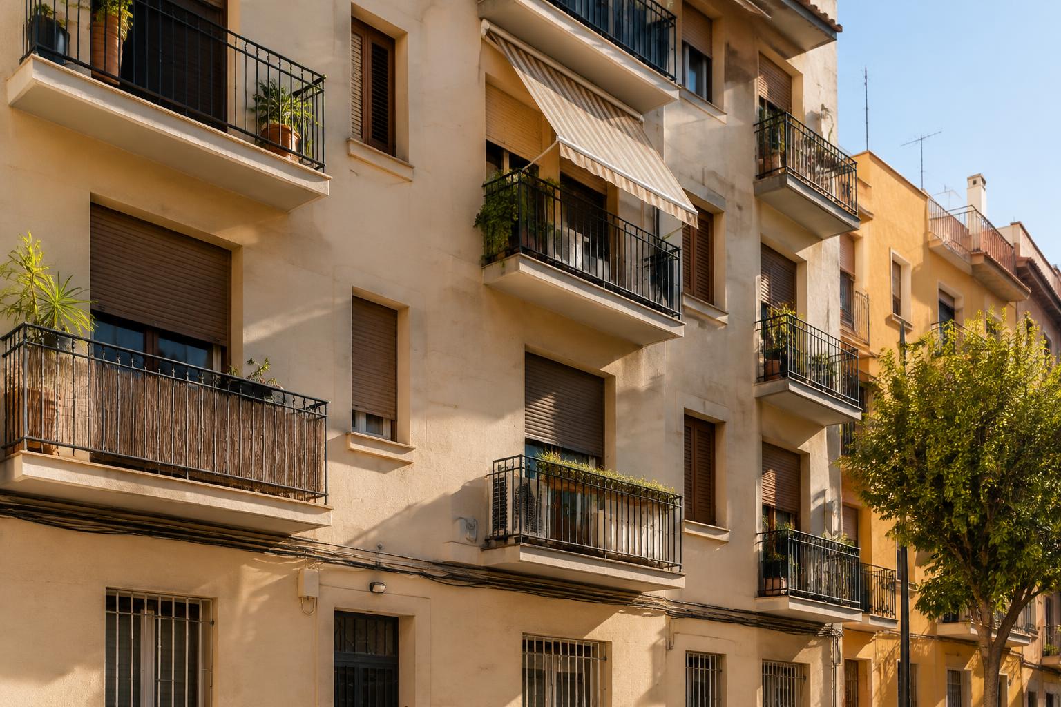 Fassade eines spanischen Mietwohnhauses mit Balkonen und Rollläden in warmem Licht (Symbolbild)