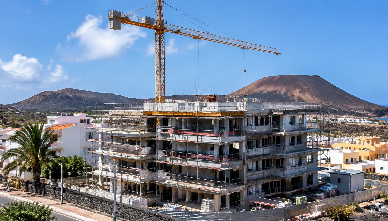 Wohnhaus im Rohbau mit Kran vor Vulkanhügeln auf den Kanaren